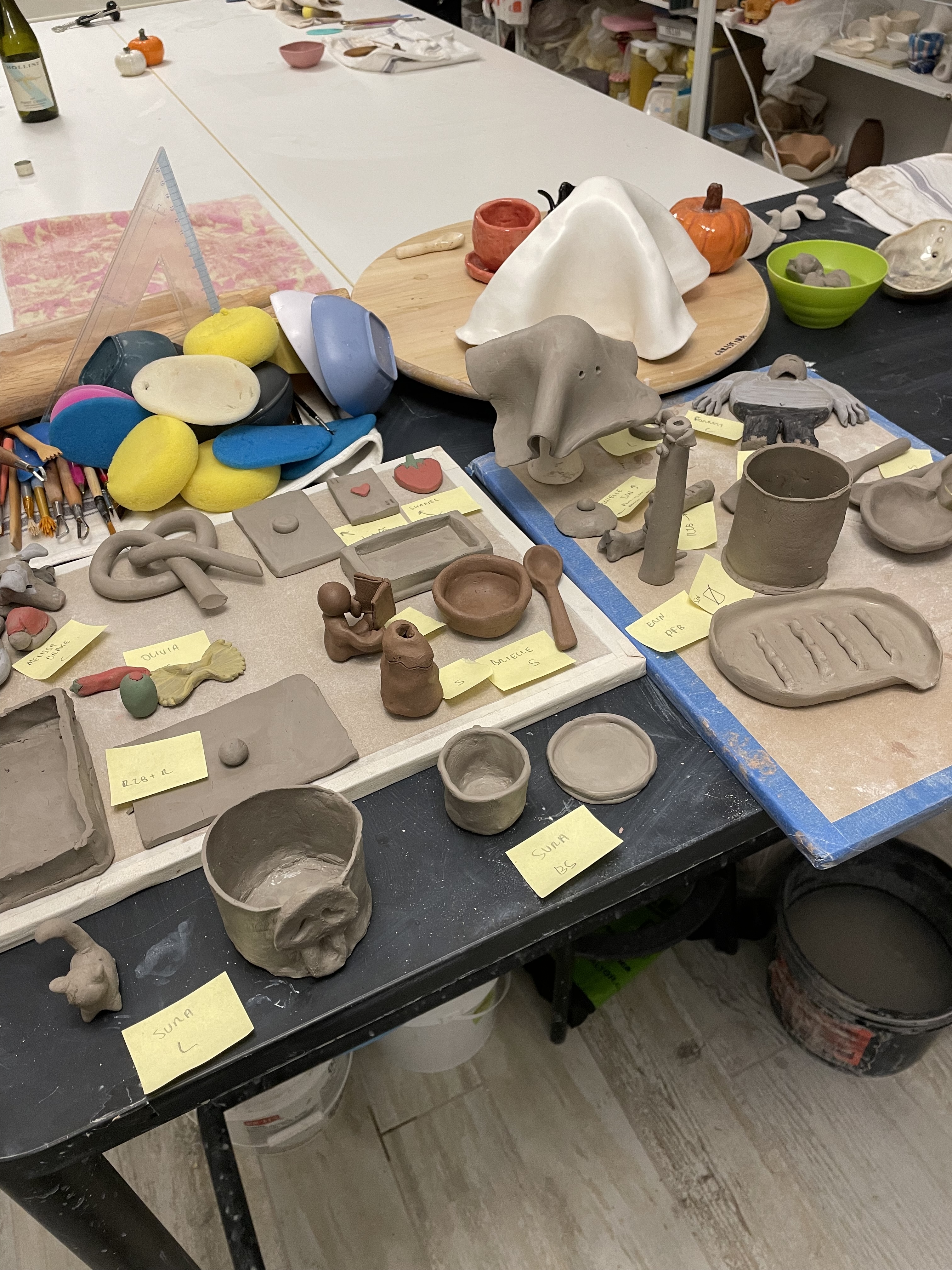 Handmade ceramic pieces, tools, and sponges laid out on a studio table.